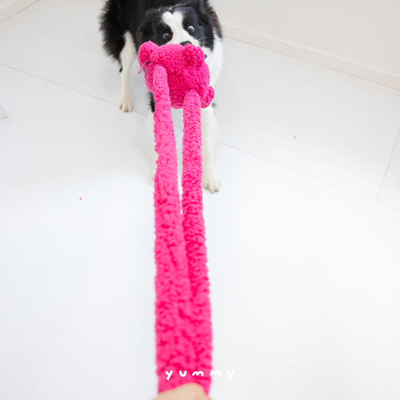 Two dogs playing tug-of-war with a durable, stretchable plush dog toy