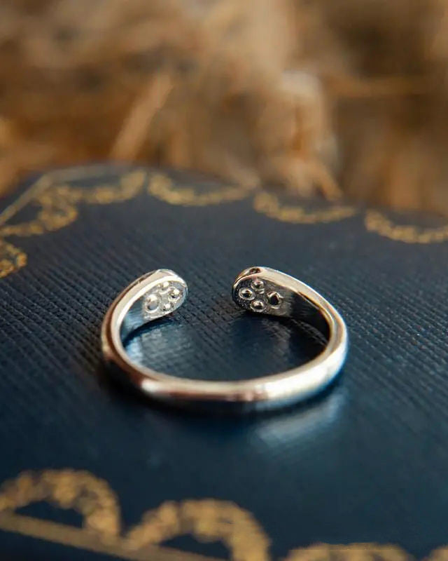 Still With Me pawprint ring resting on fabric with soft minimal styling