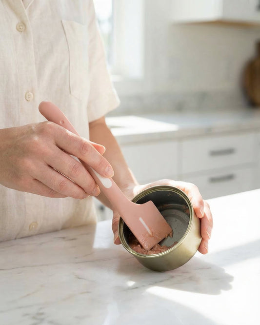 WhiskerBloom Can-Ready Spoon stirring wet pet food in a bowl on a kitchen counter